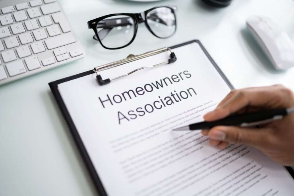 HOA paperwork on a desk with glasses and a keyboard